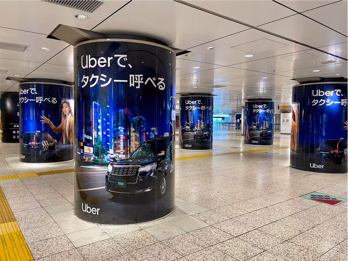 Uber Taxi station takeover: wrapped pillars reading Uberで、タクシー呼べる